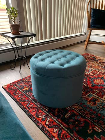 Plush, round ottoman with tufted top on a patterned rug in a cozy living room setting