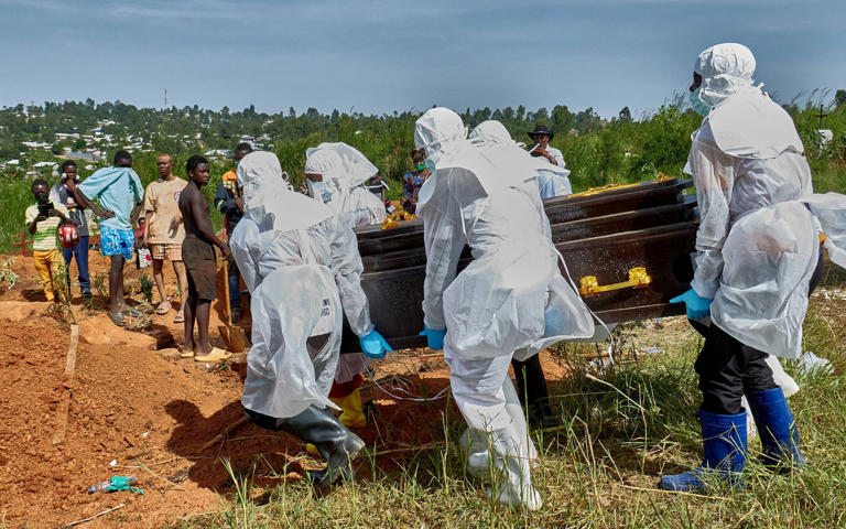 Red Cross workers wearing personal protective equipment (PPE) carry a coffin during a burial in Ituri province - Gradel Muyisa Mumbere/REUTERS