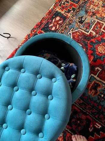 Round tufted ottoman with removable lid, revealing storage space inside, on a patterned rug