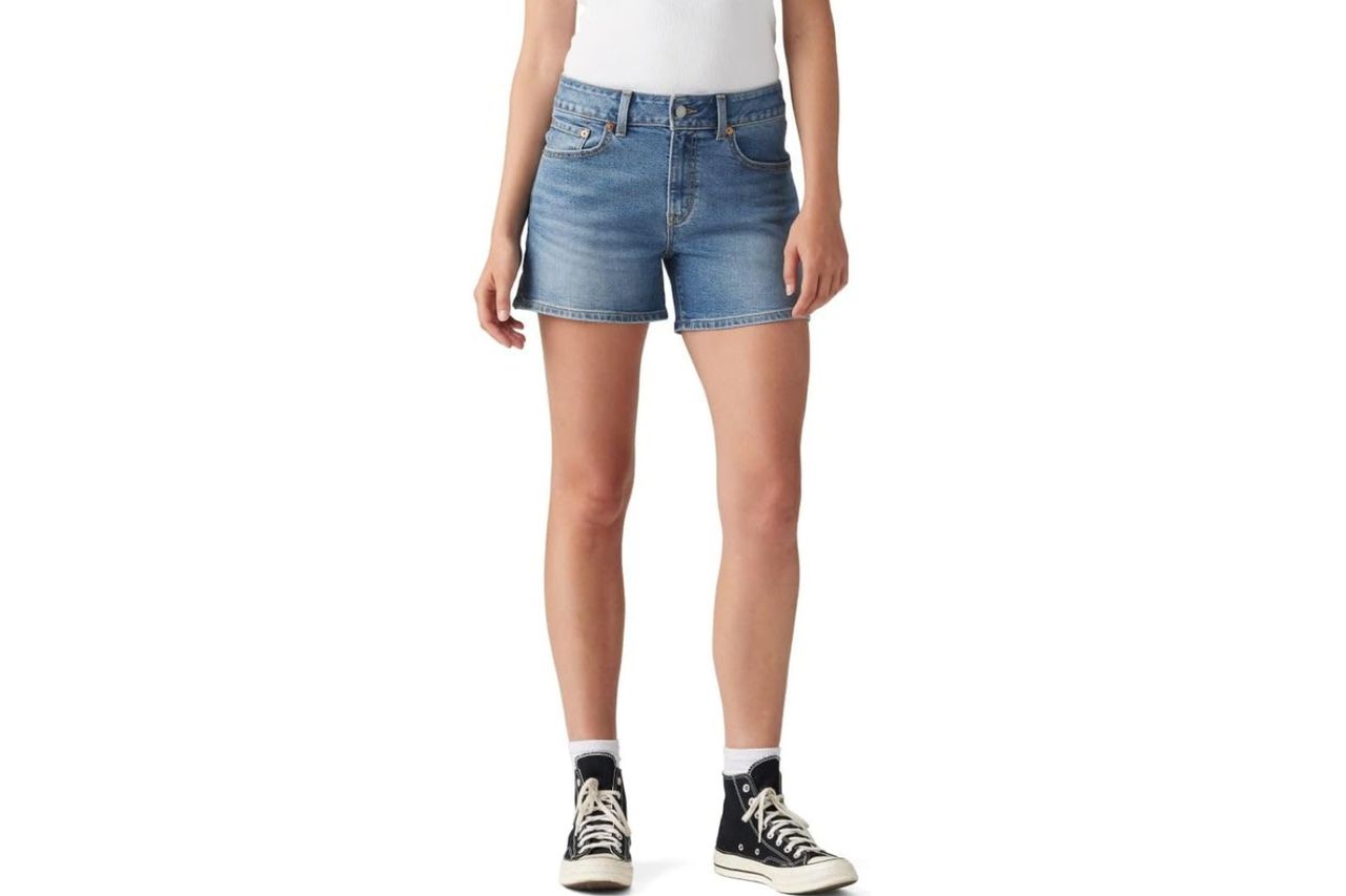 A person wearing denim shorts and sneakers