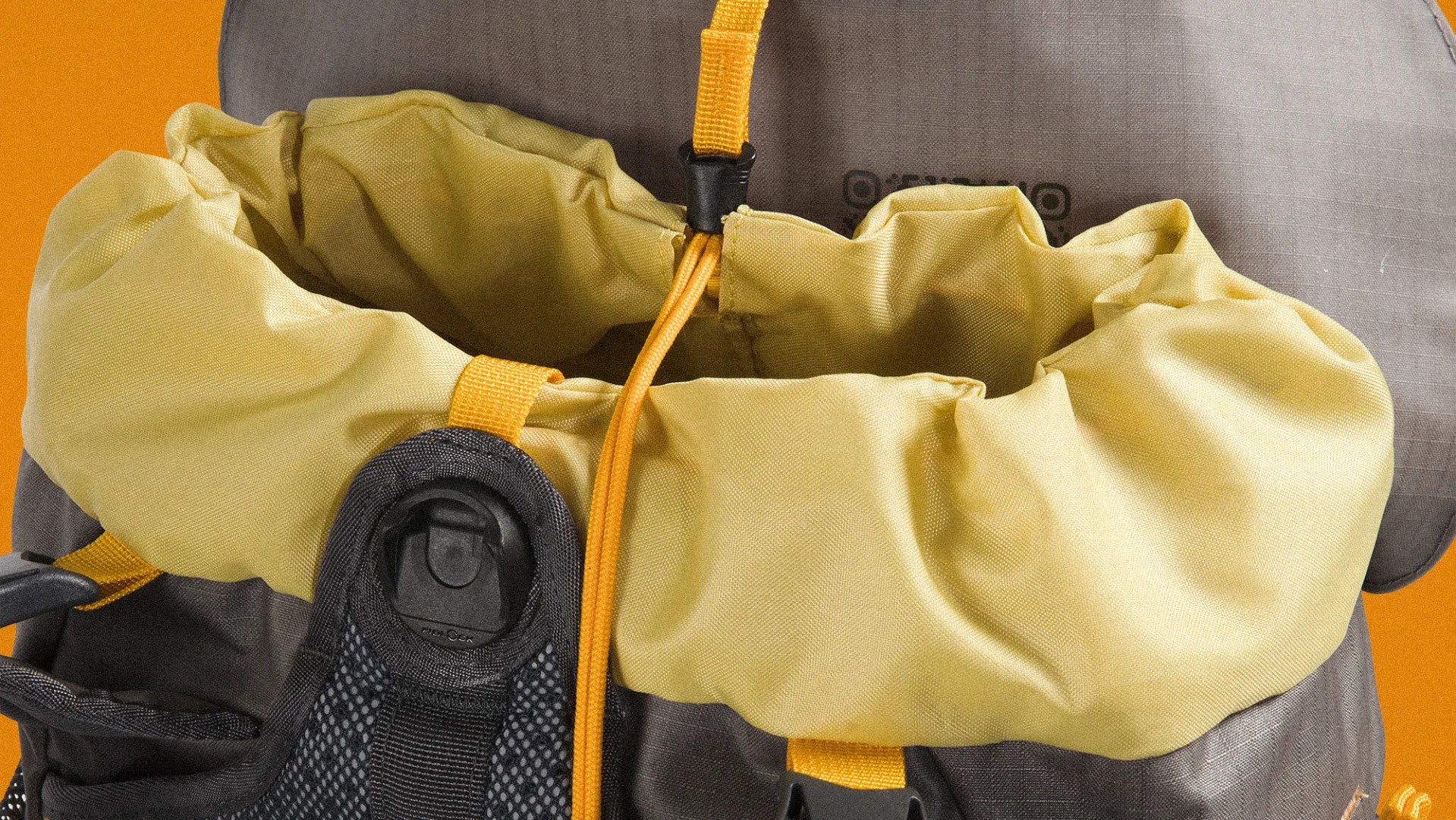 Close-up of a yellow drawstring closure on a gray and black backpack with orange straps.