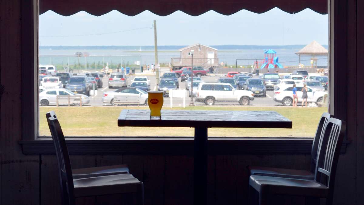 glass of beer on table overlooking beach parking lot