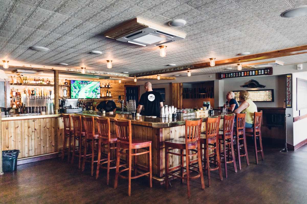 Black whale interiors with a square wooden bar with high top stools
