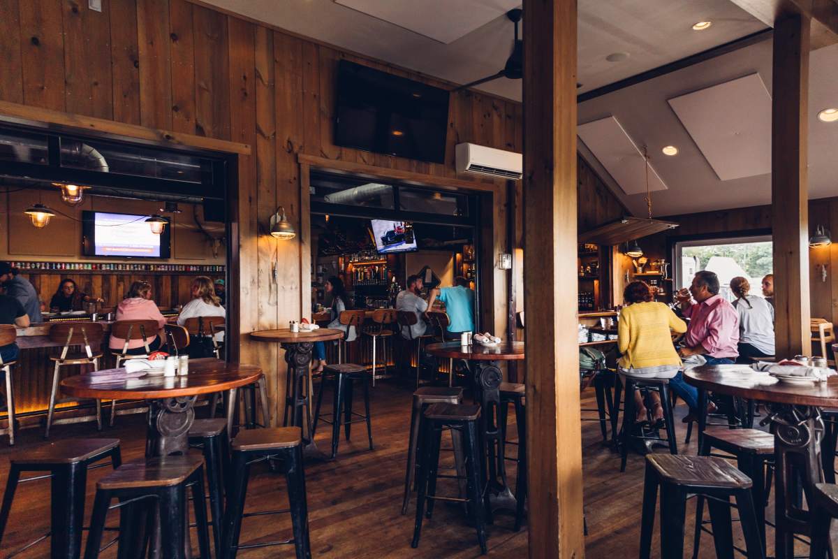 Old Causeway interiors with wood paneled walls and people seated at high top wooden tables
