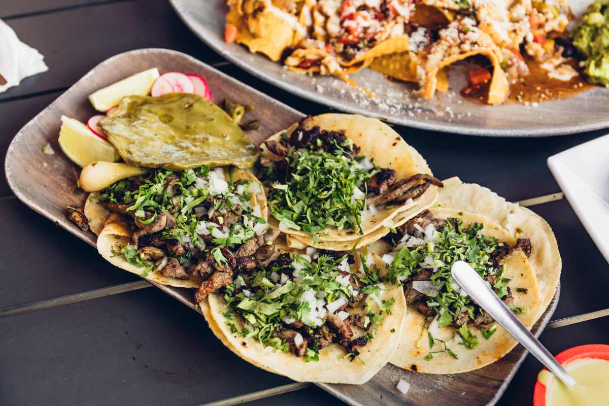 Spread of carne asada tacos topped with fresh onion and cilantro at La Cabañita