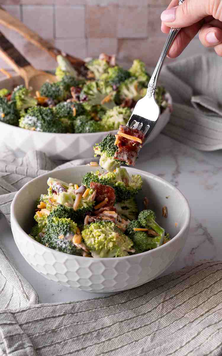 A forkful of broccoli salad with cheese and bacon.