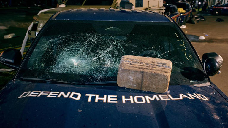 A brick sits on the hood of a damaged vehicle outside Delaney Hall following a protest Friday in Newark, New Jersey. - Andres Kudacki//AP