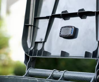 Open trash can lid with an air freshener attached inside. Sign reads: