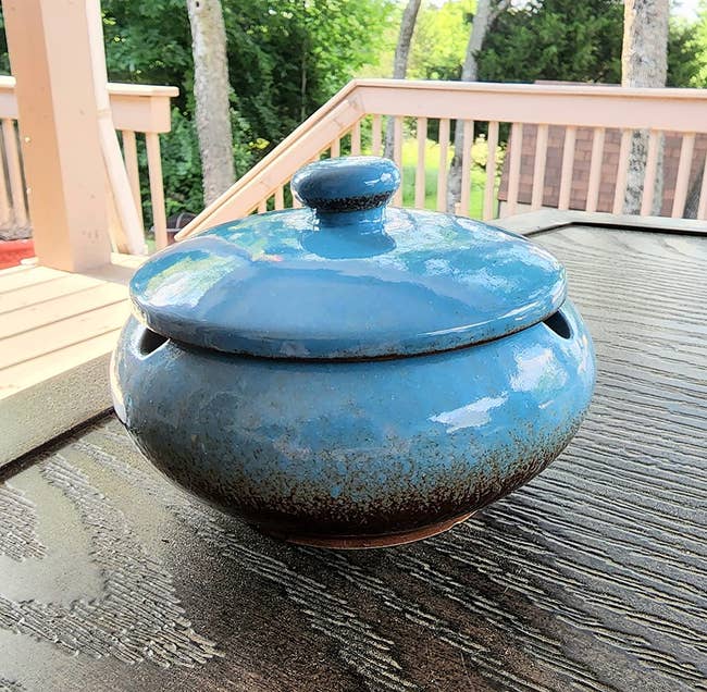 a reviewer photo of the ashtray in blue sitting on a table outside