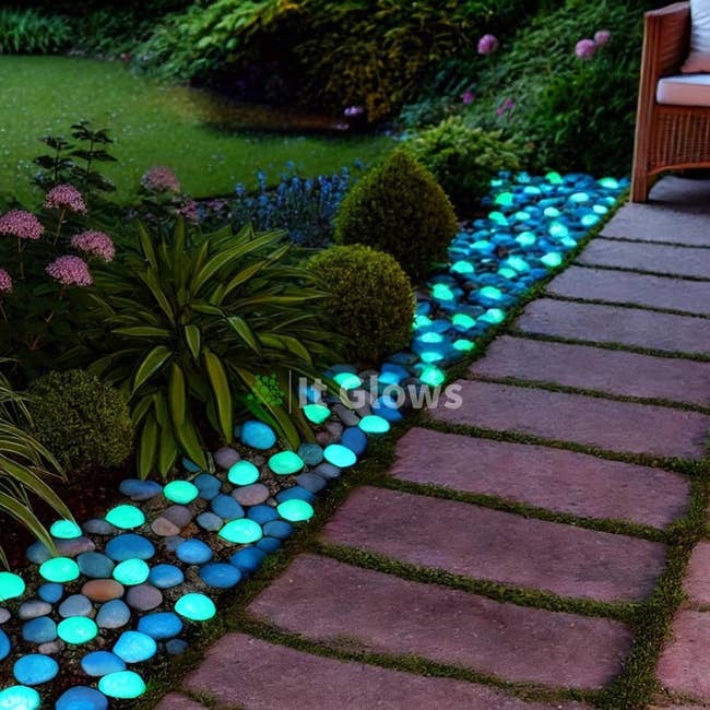 Garden path lined with glowing pebbles, creating a vibrant, illuminated border alongside plants and a seating area