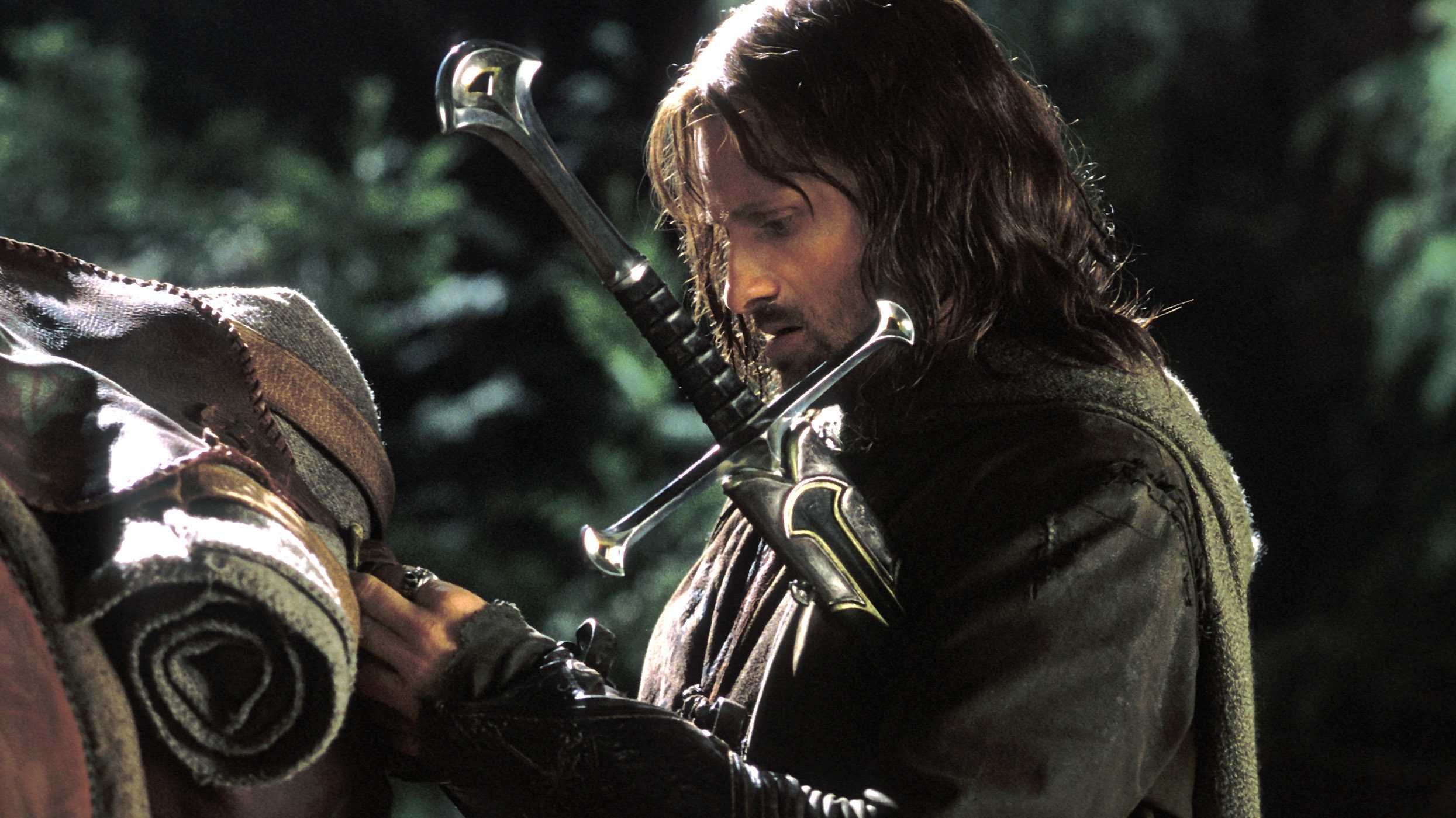Aragorn putting gear on his horse while carrying his sword under his arm in The Lord of the Rings: The Return of the King