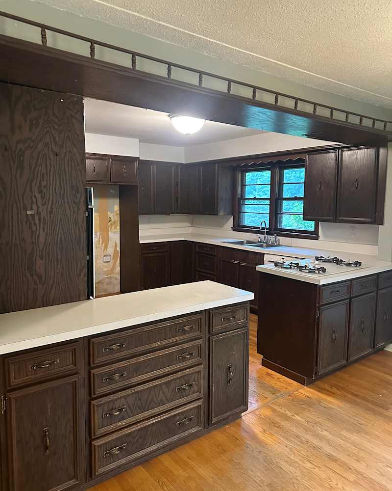 Spacious kitchen with dark wood cabinets, white countertops, and a gas stove, featuring a window above the sink.