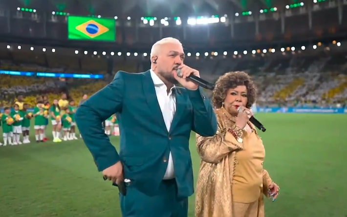 Belo e Alcione cantam o hino nacional brasileiro durante jogo do Brasil no Maracanã. Foto: Reprodução de 'Brasil x Panamá' (2026)/TV Globo