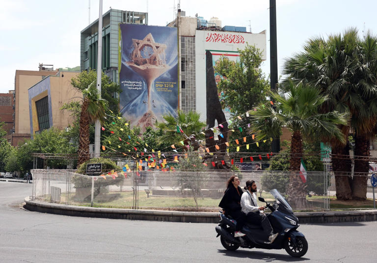 Iranians drive in front of an anti-Israeli billboard hanging in Palestine Square in Tehran, Iran, on May 28. The text says that Israel