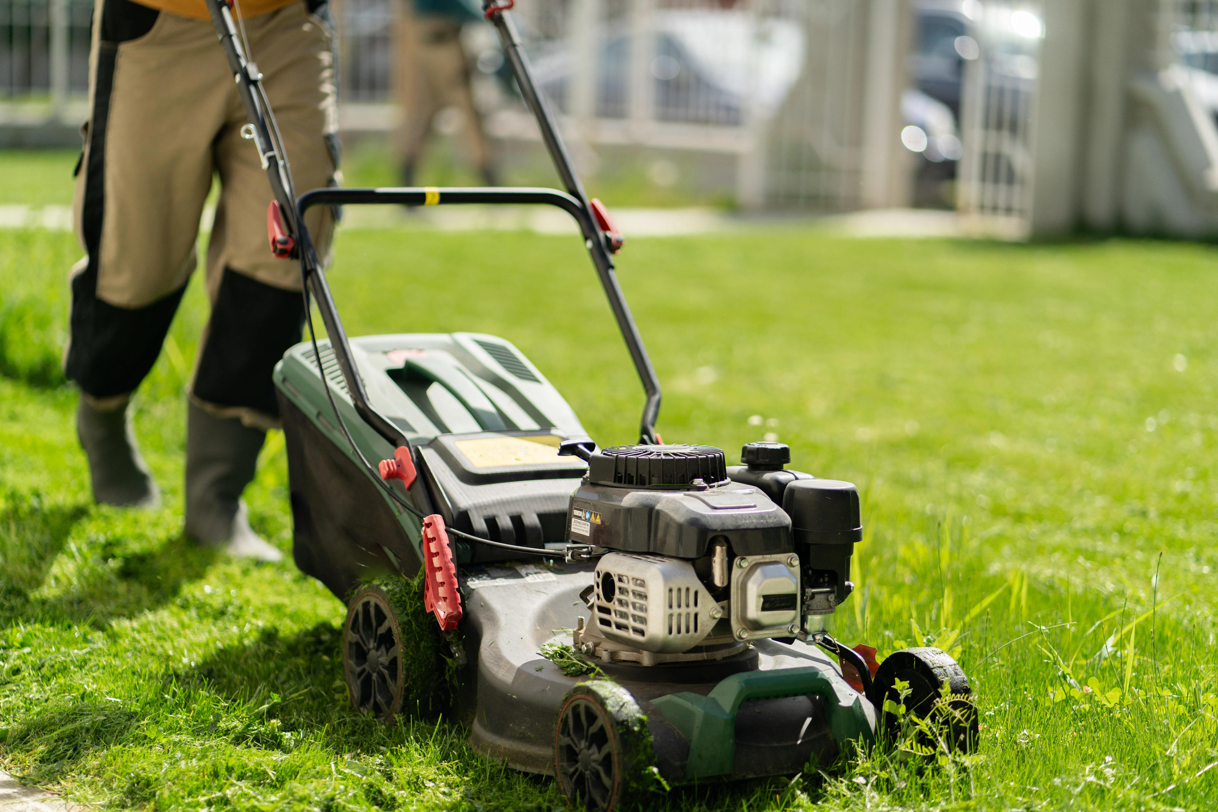 A person pushing a mower in a yard is shown.