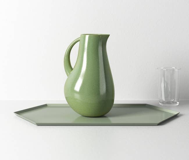 Elegant ceramic pitcher on hexagonal tray with a glass beside it
