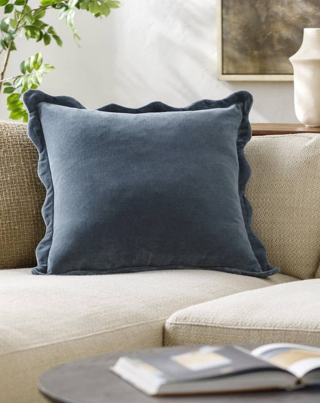 Plush velvet pillow with wavy edges on a beige sofa, creating a cozy living space