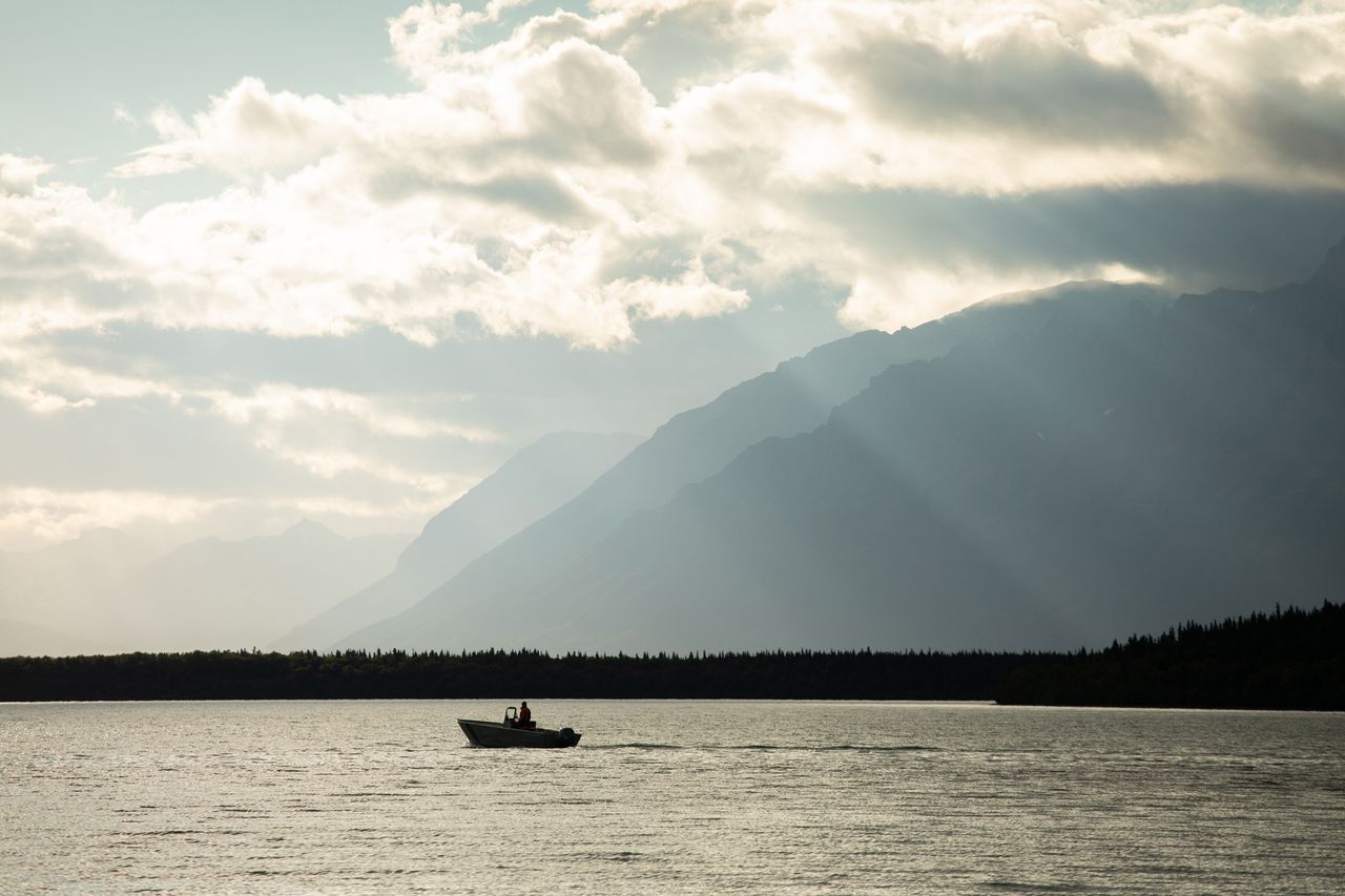 A small boat on a river with mountains in the background