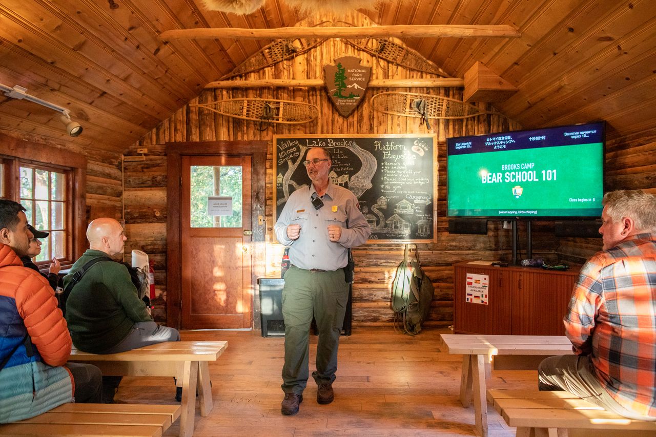 A park ranger giving a presentation on bear safety to a small group inside a wooden cabin