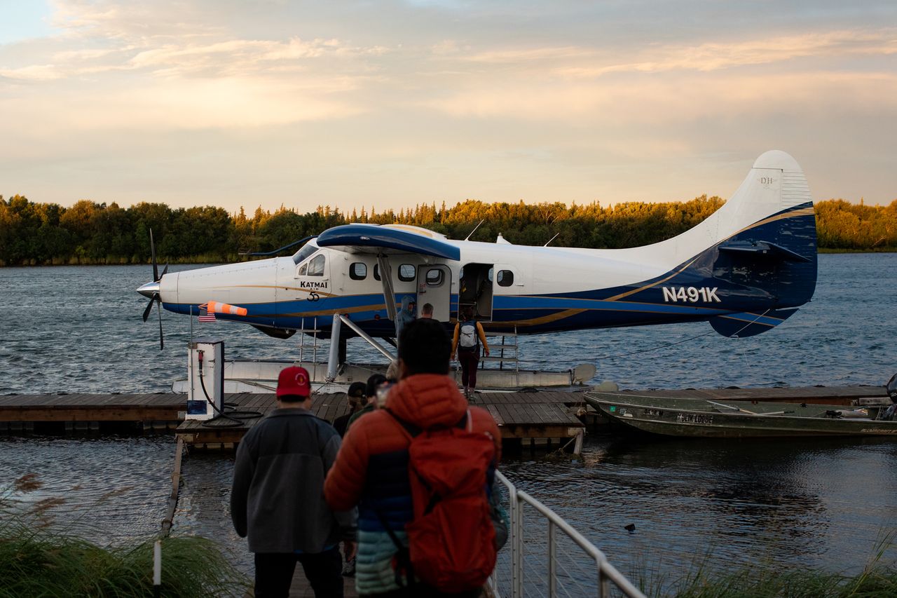 A group of people walking along a dock toward a docked seaplane on the water