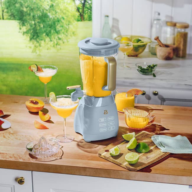 Blender on a kitchen counter making smoothies, surrounded by fresh citrus fruits and glasses with juice, set in a bright kitchen