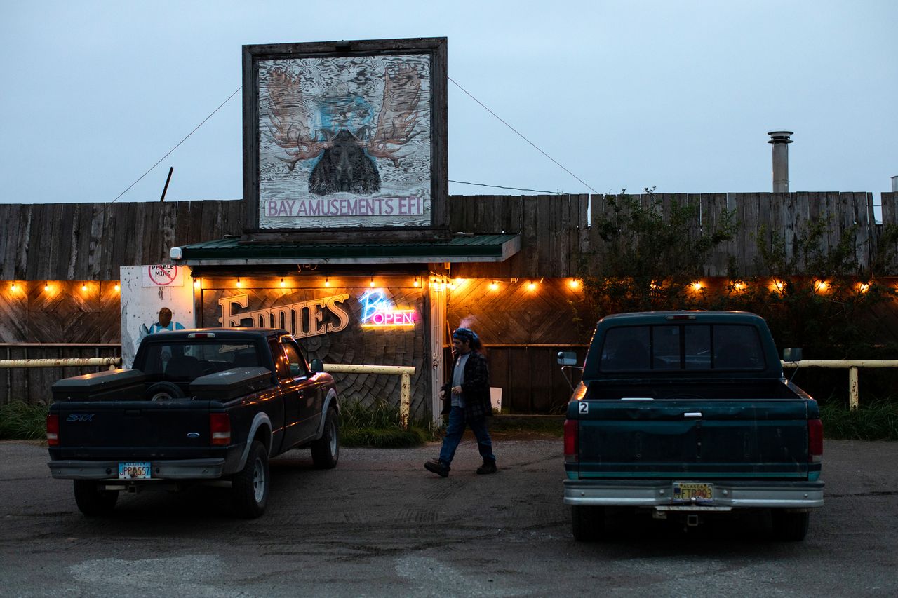 Person walking between parked trucks outside an illuminated establishment