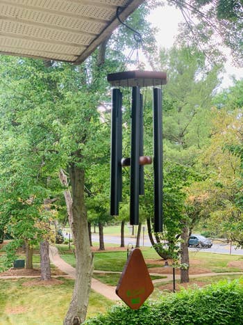Wind chime hanging outdoors, surrounded by trees, creating a serene, natural setting