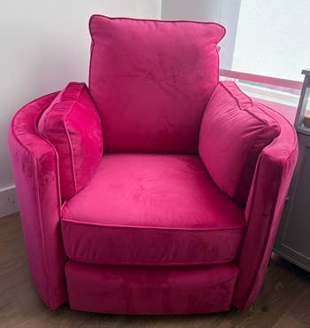 Plush, pink cushioned chair with wide armrests