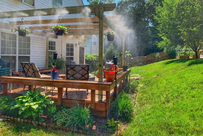 Reviewer's patio with with misting system installed and lightly spraying