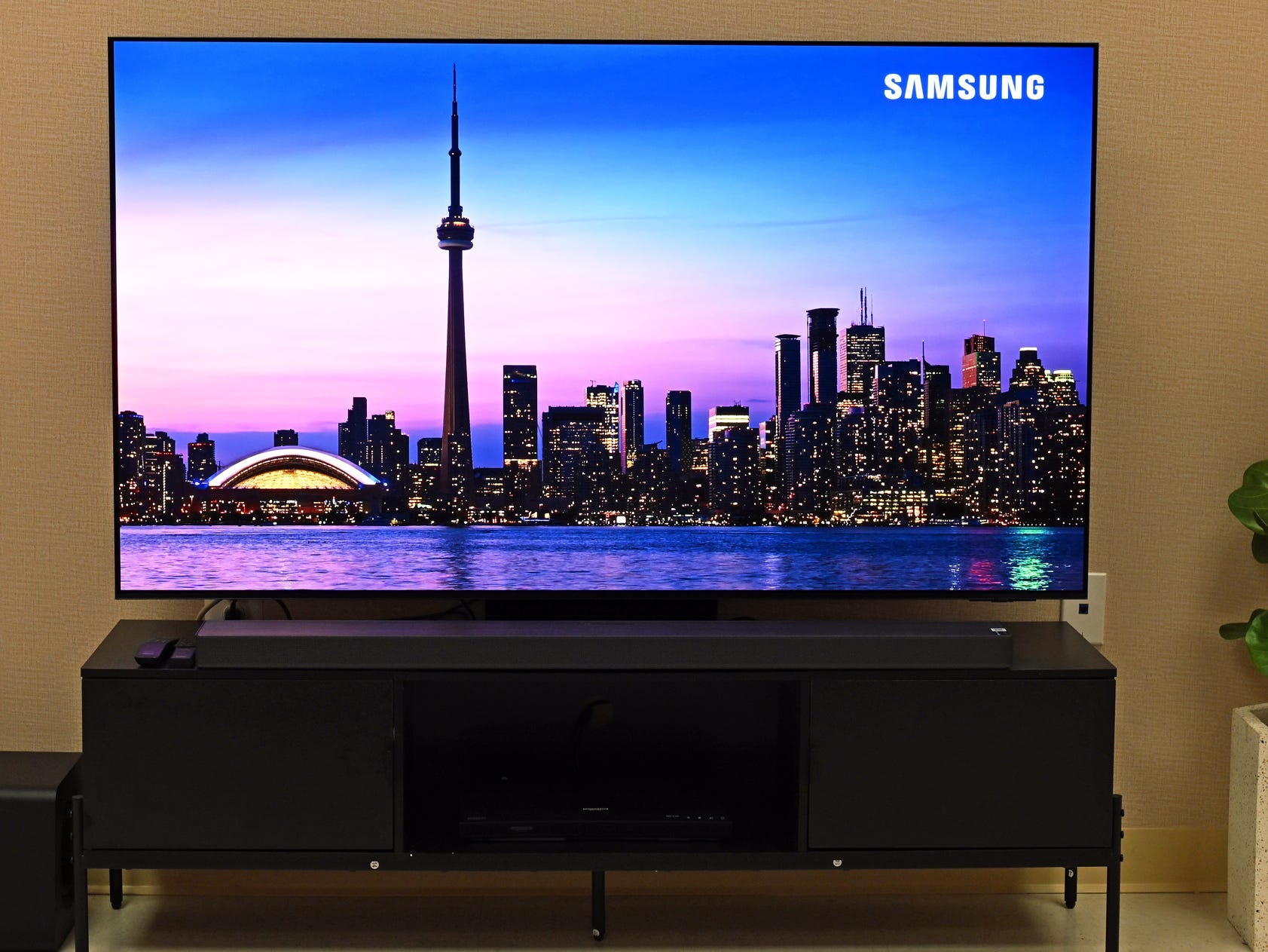 A Samsung S95F TV displaying a video of a cityscape at night.
