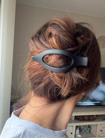 reviewer with hair in a bun secured by a large, black hair clip, in a casual indoor setting