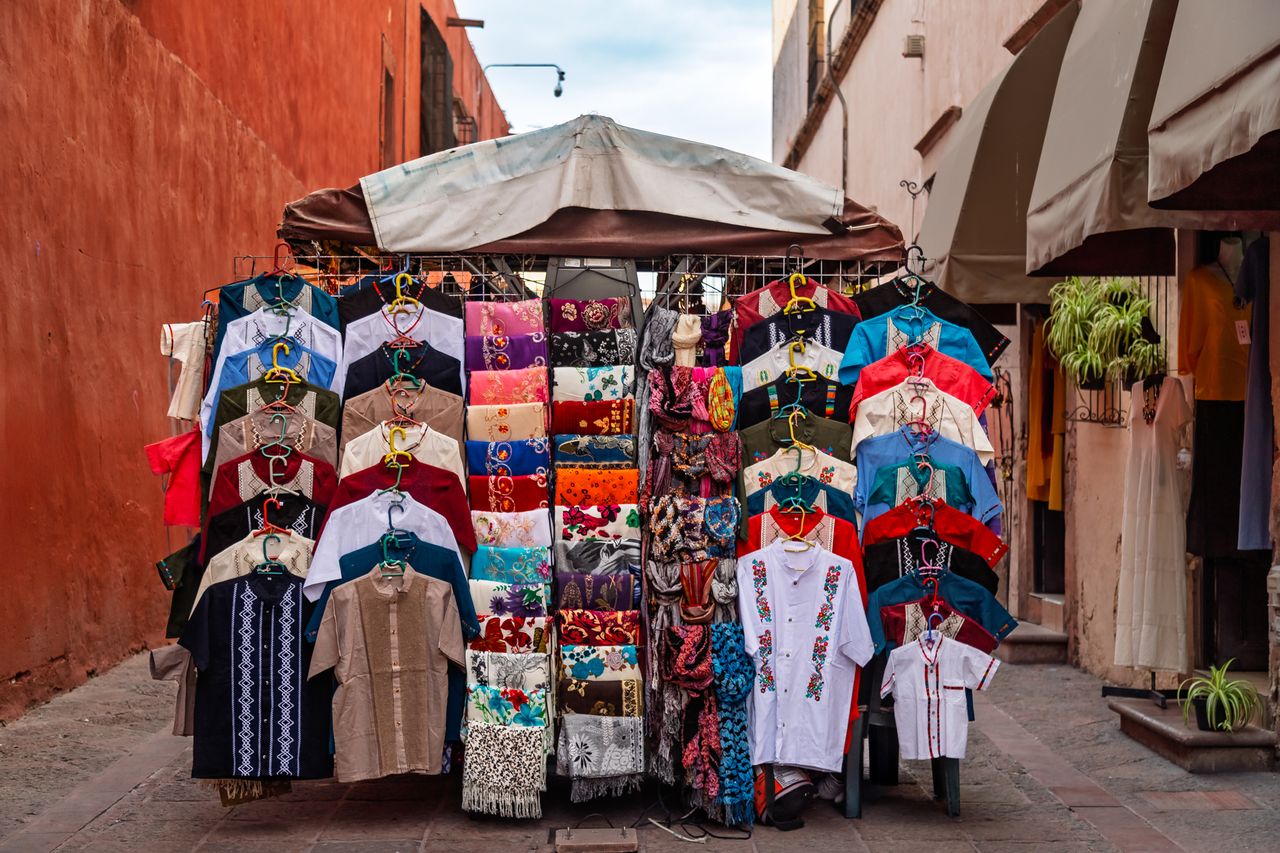 A market stall showcasing an array of colorful clothes and textiles in a street setting