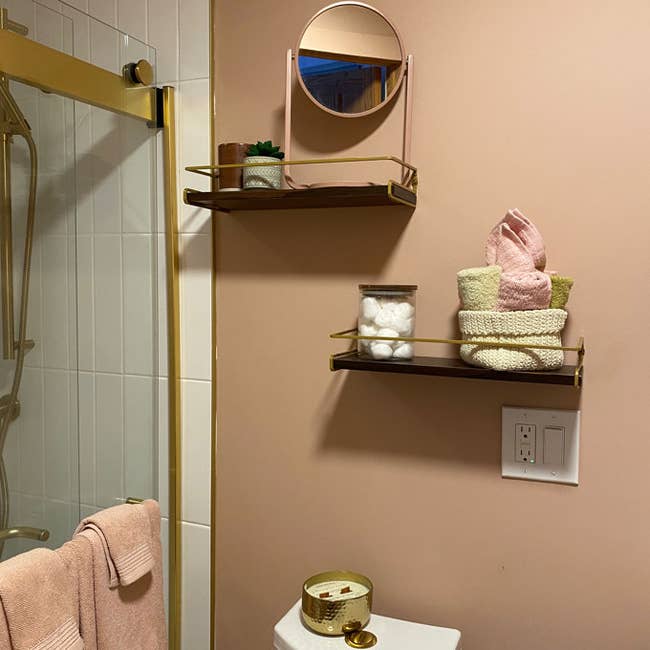 Bathroom shelves with mirror, succulent, towel, and bath essentials organized neatly above a toilet, showcasing home decor items for sale
