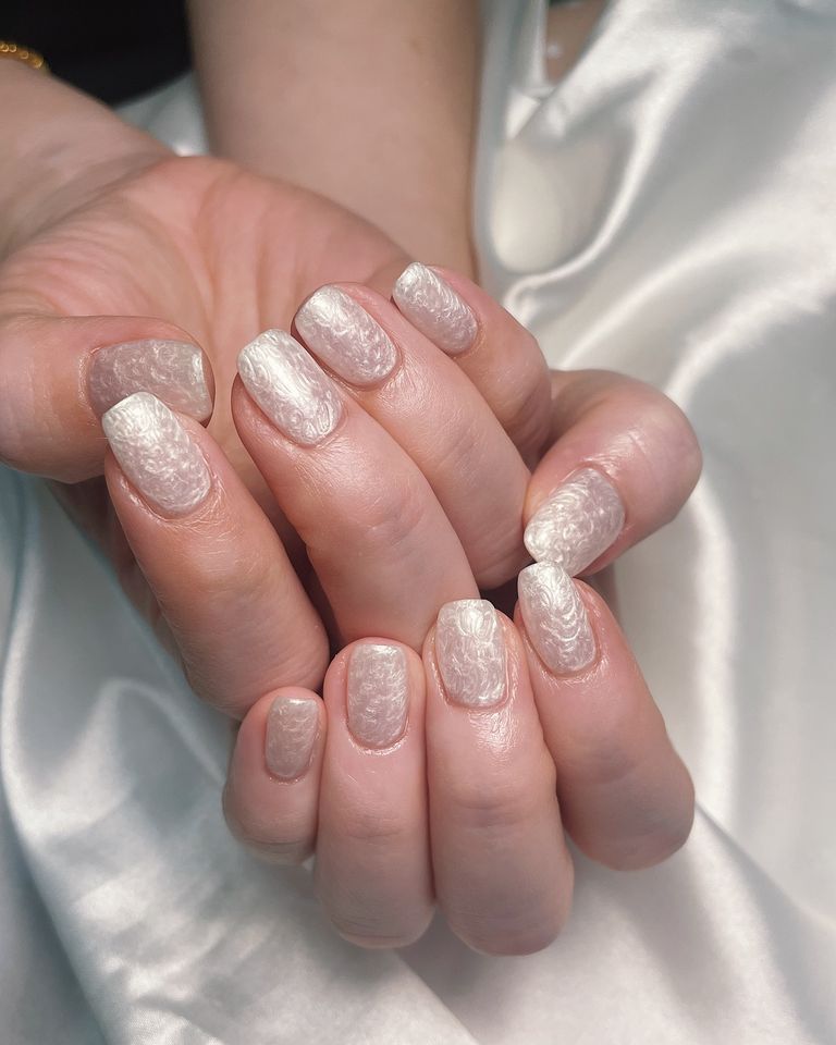 Closeup of hands showcasing manicured nails with detailed designs
