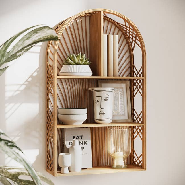 Woven wall shelf with books, succulents, and decorative vases styled for a modern, bohemian aesthetic