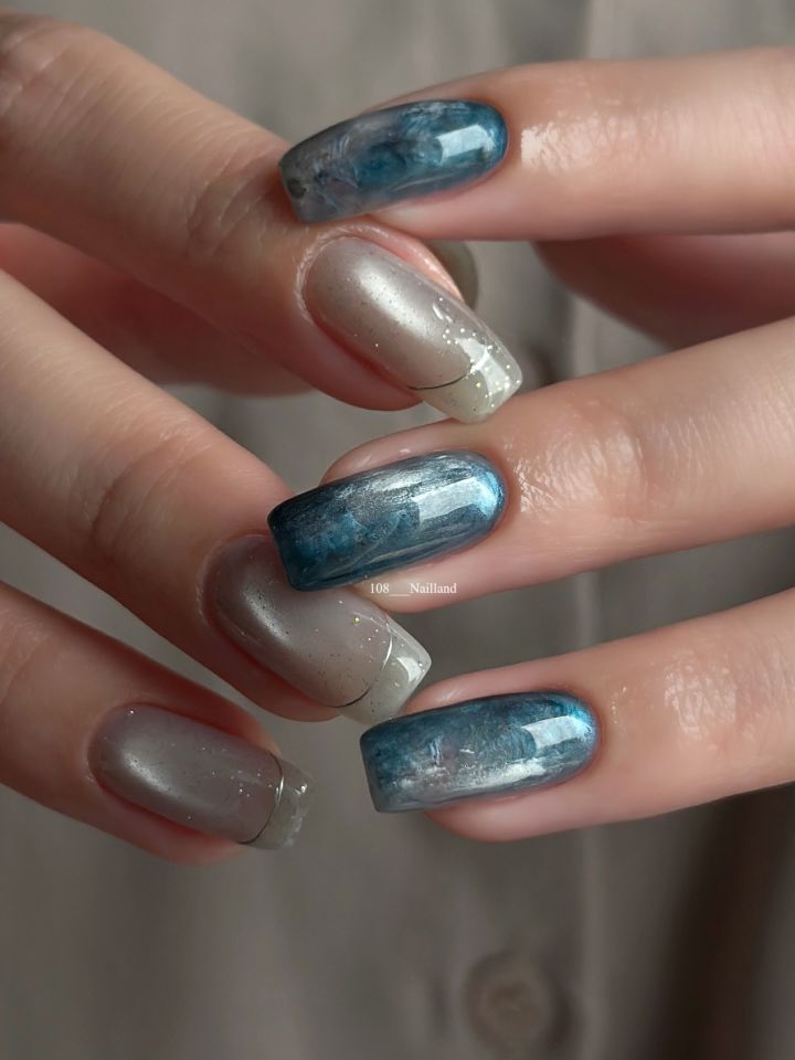 Hands displaying manicured nails with intricate designs on some nails closeup view