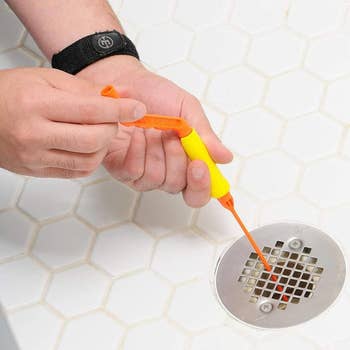 A model feeding the drain snake down the drain and using the handle to turn it
