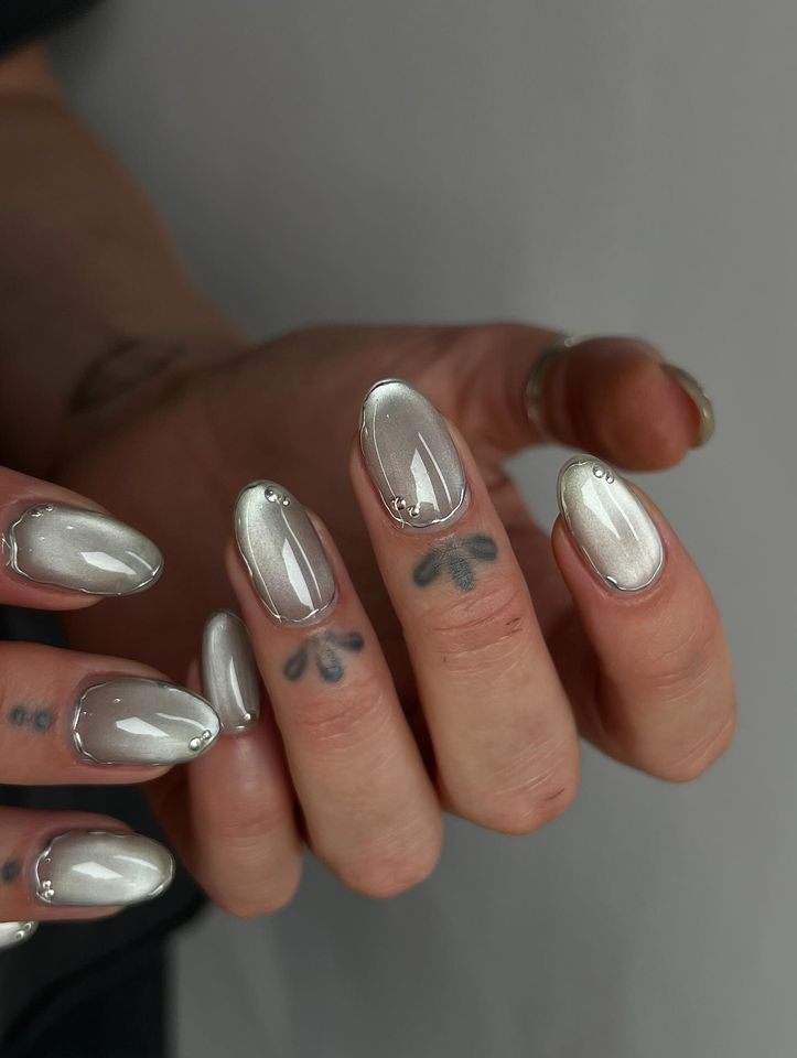 Closeup of hands with metallic nails and small tattoos on fingers