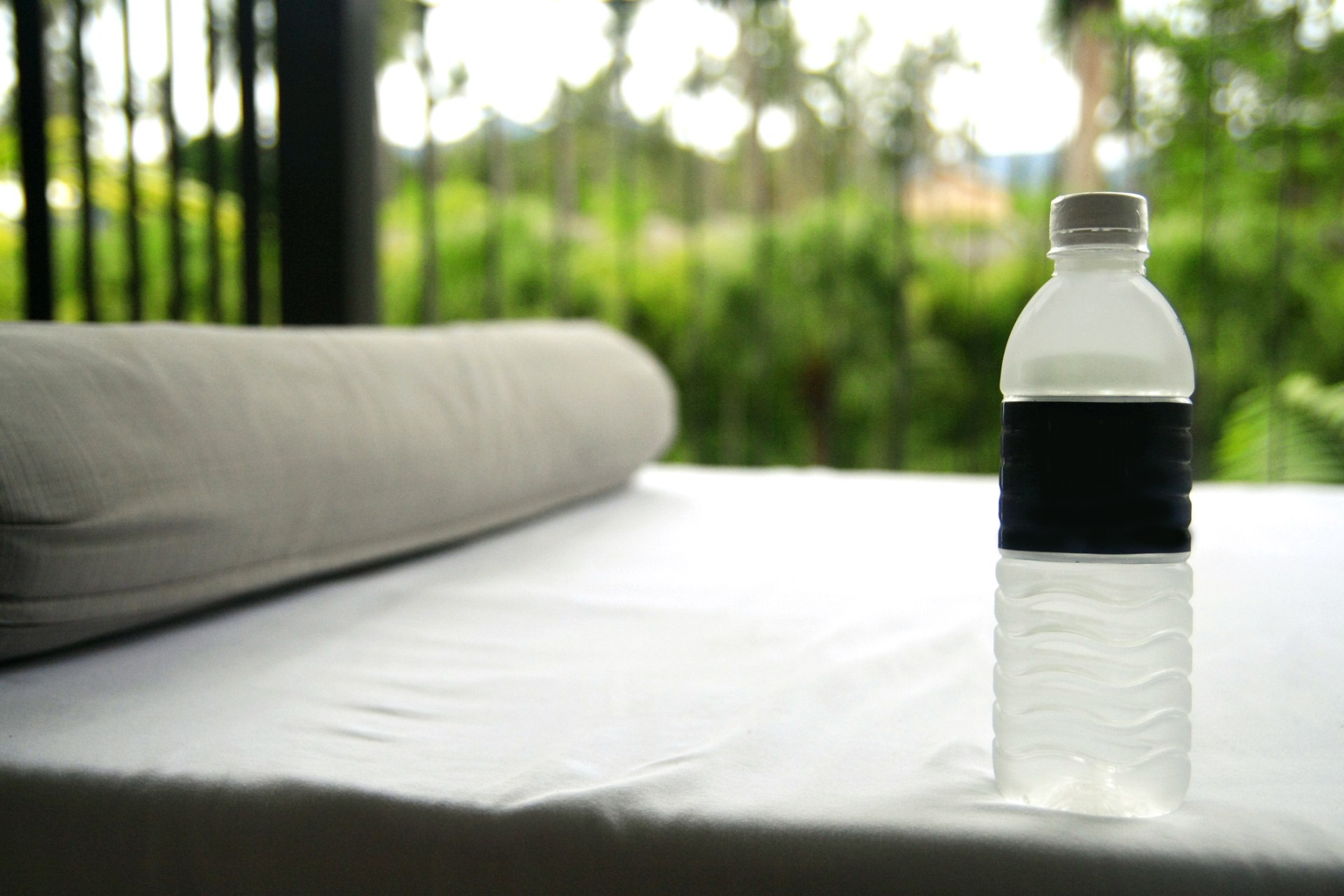 A water bottle standing on a hotel bed.
