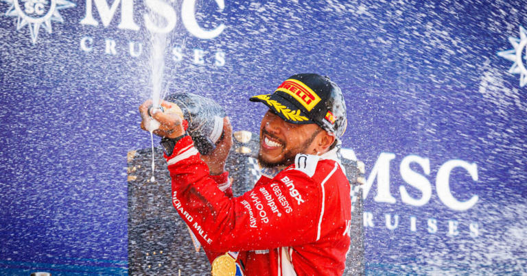 Lewis Hamilton with a huge smile sprays champagne his debut Ferrari win on the podium