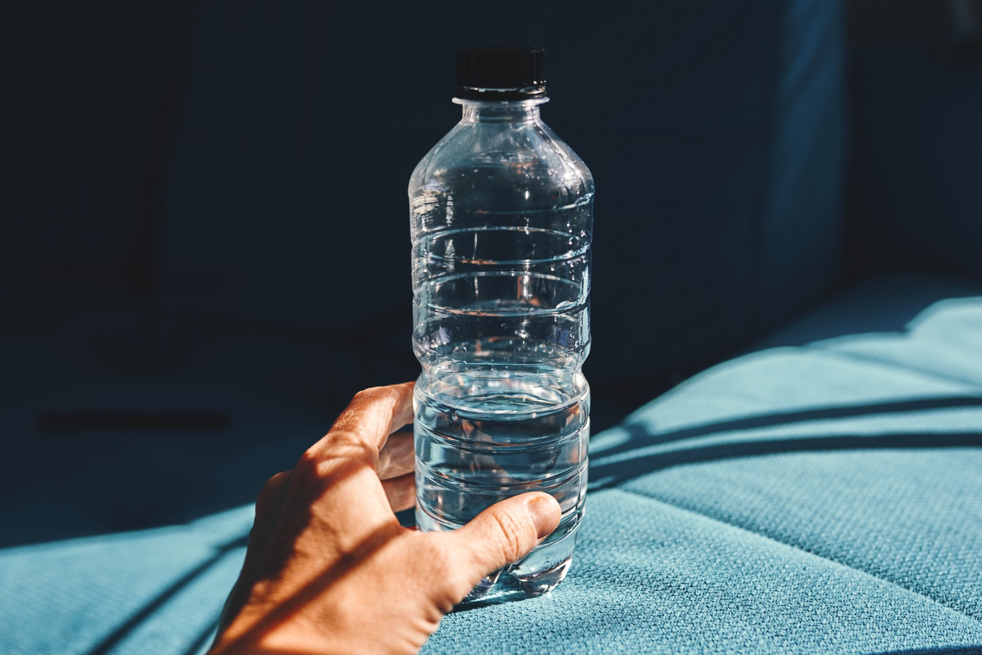 Water bottle held in hand on a hotel bed