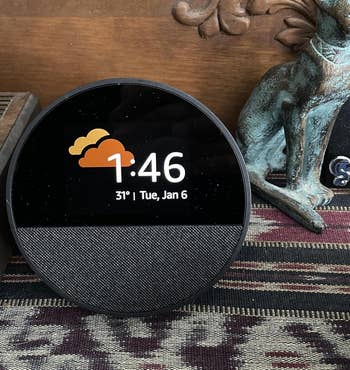 Smart display shows time 1:46, date January 6, and 31°F with cloud icon, set on a patterned surface with decorative items nearby