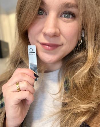 Person holding e.l.f. lipstick near face, showcasing product for a shopping feature