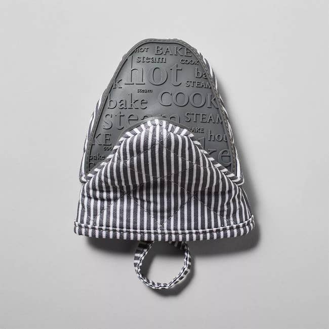 A textured oven mitt with striped fabric and loop, featuring raised cooking-related words like bake and cook