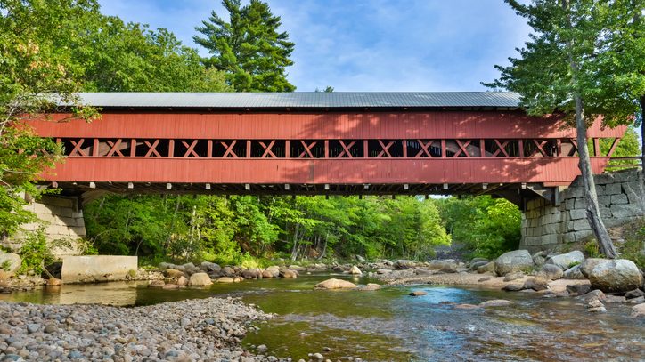 A historic red covered bridge goes over a stream in North Conway, New Hampshire.