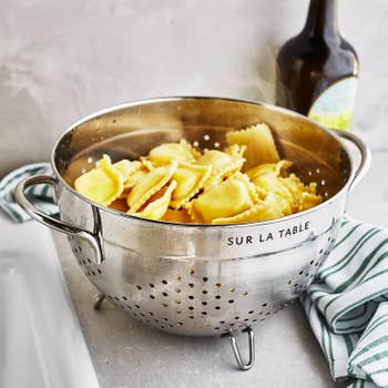 Ravioli draining in a stainless steel colander labeled