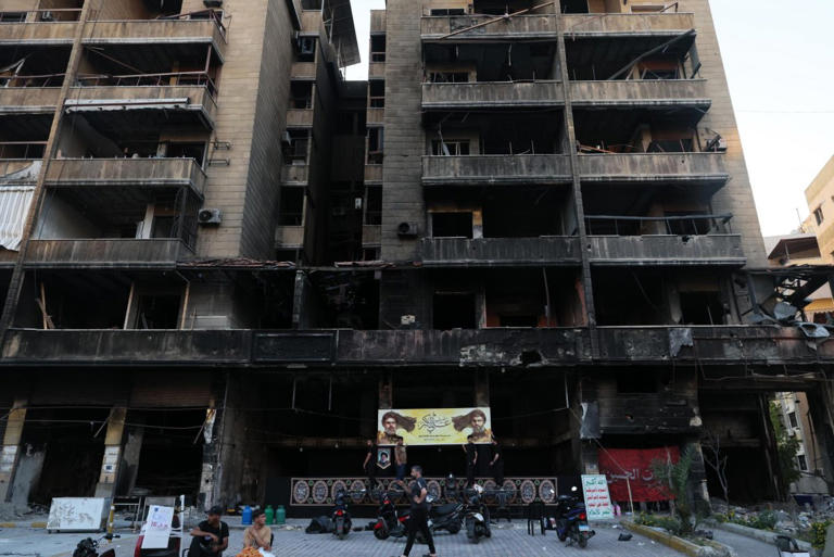 Supporters of Hezbollah hang a banner depicting portraits of late Hezbollah leaders Hassan Nasrallah (R) and Hashem Safieddine in a partially damaged building targeted by an Israeli strike, during the first day of Ashura in the southern suburbs of Beirut, Lebanon, Wednesday. Israel and Lebanon have been trading strikes for several days.