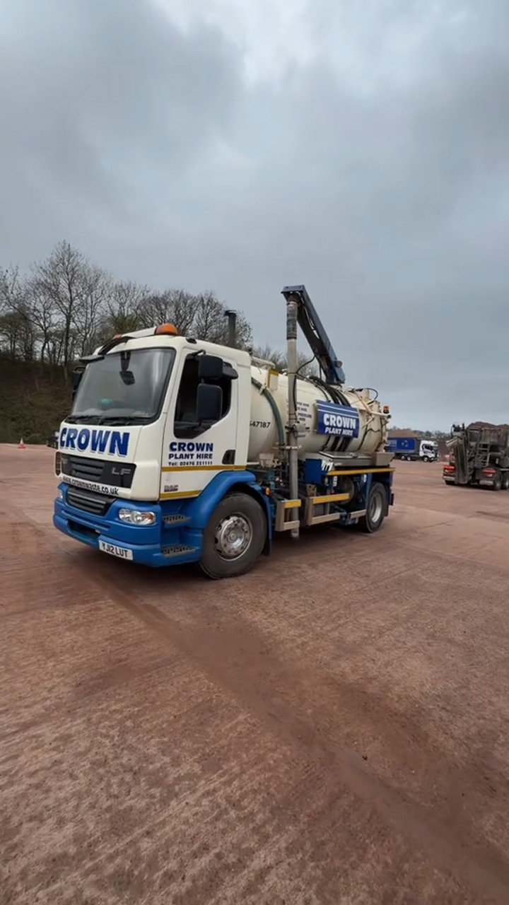 Massive industrial suction truck maneuvers through a dirt yard