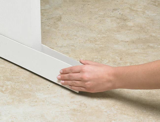 Person installing white draft stoppers on the bottom of a door