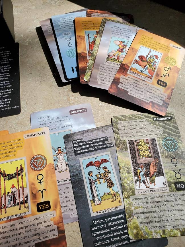 Tarot and oracle cards spread out on a surface, showing illustrations and keywords like